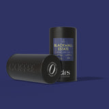 Two black cylindrical containers filled with 100% home compostable, Nespresso® compatible coffee pods with 'Blackwall Estate' label on a purple background.